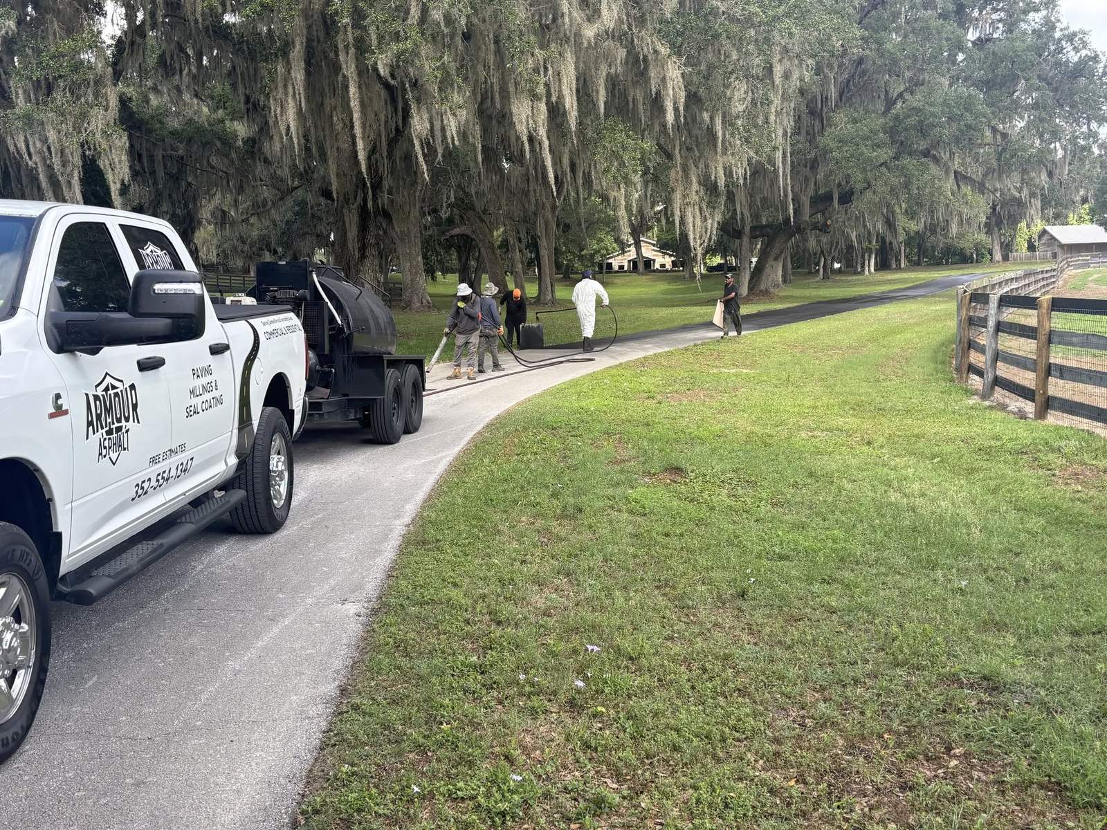 Armour truck and crew sealcoating a long horse farm driveway