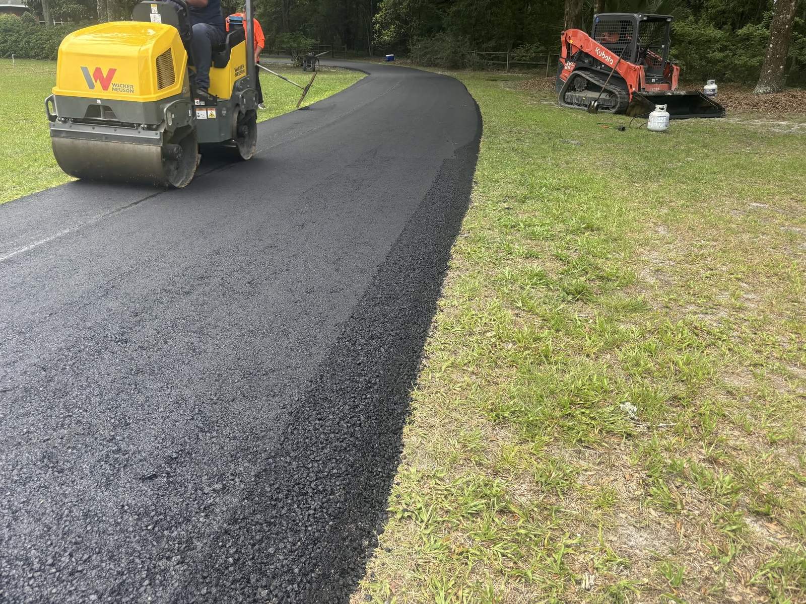 Roller compacting a fresh asphalt overlay on a driveway