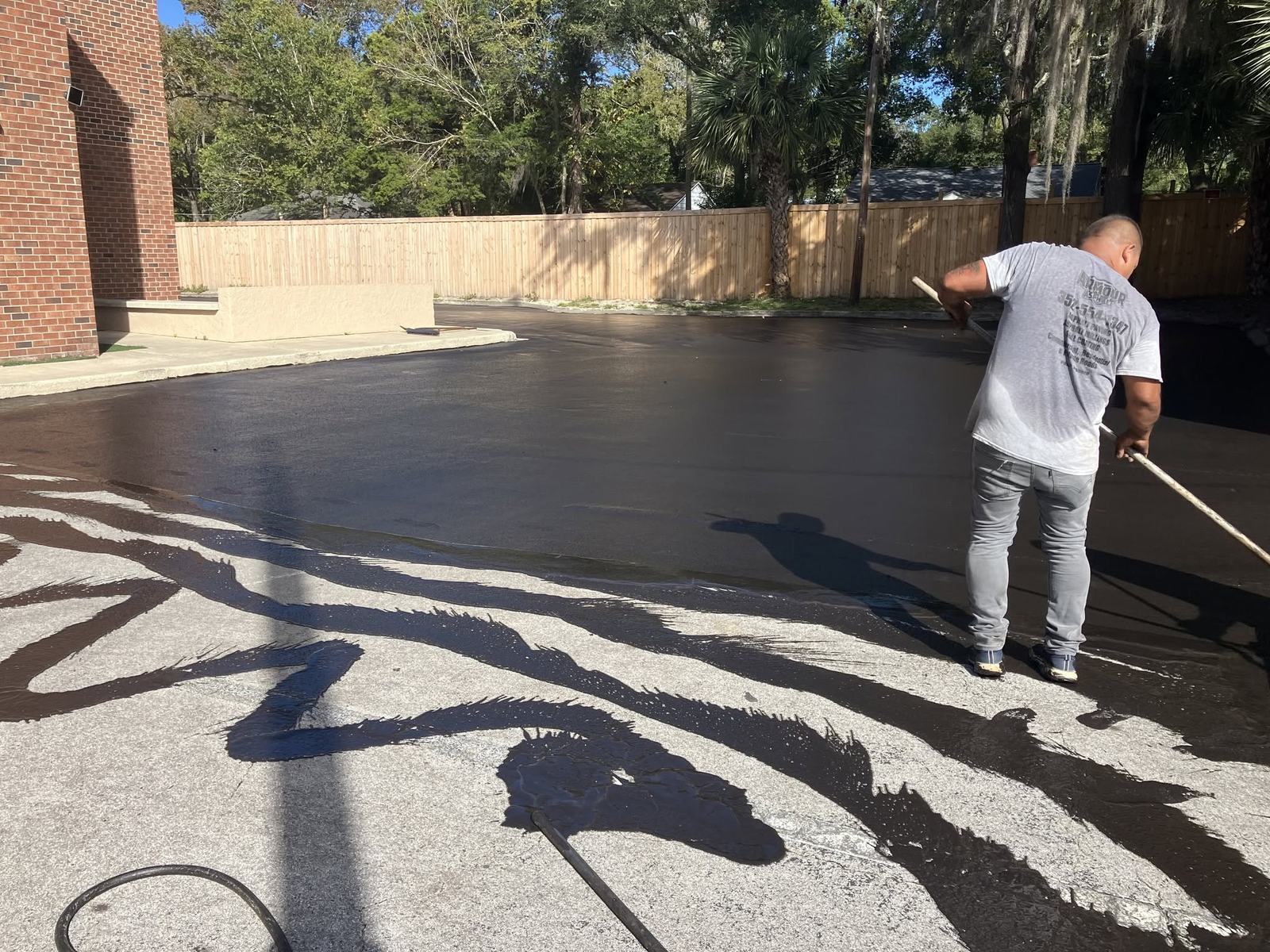 Armour crew hand-applying sealcoat to a commercial lot in Gainesville